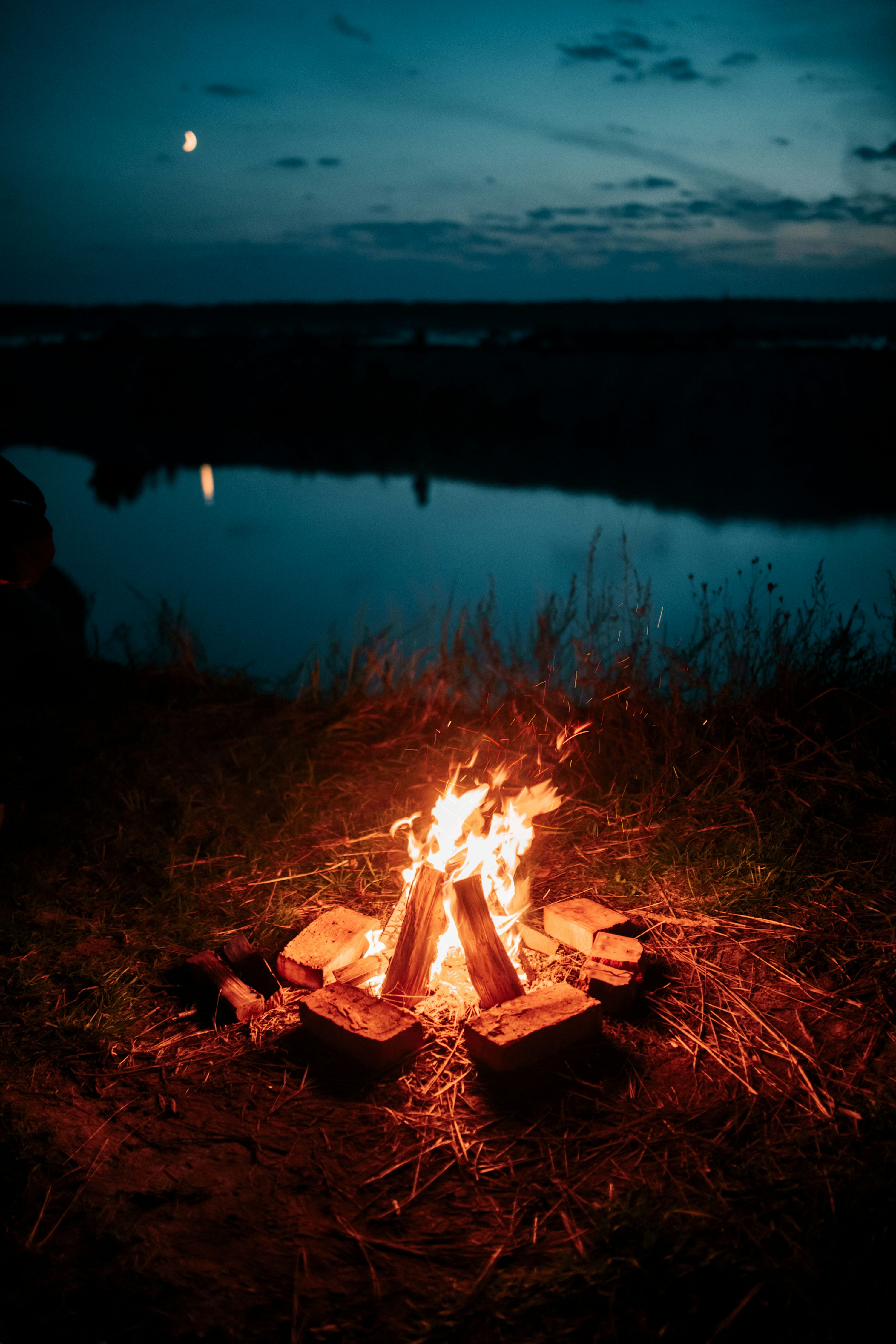 A glowing campfire beside a lake at dusk; fireside inspiration